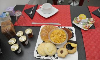 a table is set with a variety of breakfast items , including croissants , biscuits , jams , and coffee at Magic Rainbow