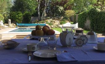 a table is set with a blue cloth , white plates , and bowls in front of a pool at Le Numero 15
