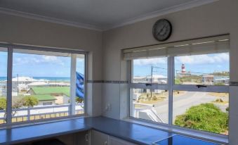a kitchen with a window overlooking the ocean , and a clock on the wall near the window at South Point Guest Lodge