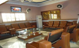 a well - lit waiting room with leather couches and chairs , as well as a tv mounted on the wall at Royal Inn