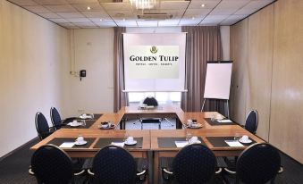a conference room with a table , chairs , and a large screen displaying the golden tulip logo at Gr8 Hotel Sevenum