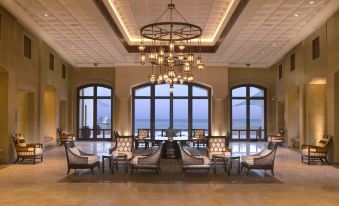 a luxurious hotel lobby with high ceilings , large windows offering views of the ocean , and comfortable seating arrangements at Anantara Desert Islands Resort & Spa