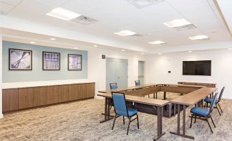 a conference room with a long table and chairs , a screen on the wall , and framed pictures at Staybridge Suites Denver North - Thornton