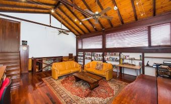 a living room with wooden floors and walls , orange leather couches , a coffee table , and bookshelves at Karriview