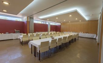 a large , empty conference room with multiple white chairs and tables set up for an event at Amazonia Palmela Apartamentos Turisticos