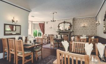 a well - decorated dining room with wooden chairs and tables , creating an elegant atmosphere for guests at The Bentley Brook Inn