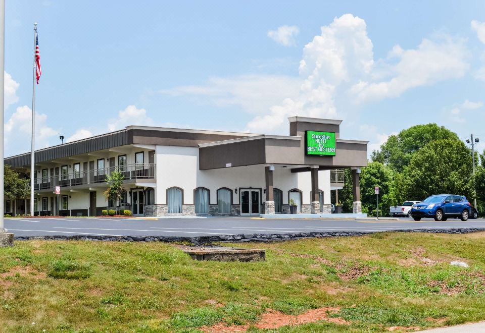 a large , white and gray motel with a green sign on the side of the building at SureStay Hotel by Best Western Bowling Green North