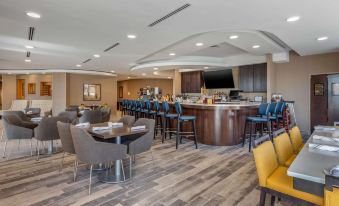 a modern , well - lit bar with various seating options and a large bar area with chairs at Cambria Hotel West Orange