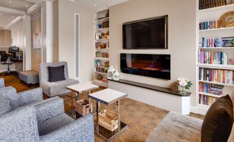 a modern living room with a large flat - screen tv mounted on the wall , surrounded by comfortable couches and chairs at Best Western Plus Longbranch Hotel  Convention Center