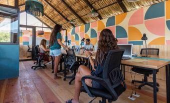 a group of people sitting around a long table in an office setting with colorful walls at Selina Atitlan