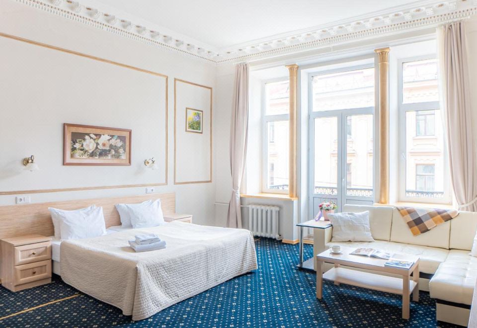 a hotel room with a large bed , two chairs , and a window overlooking the city at Alexander Hotel