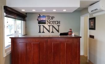 "a reception area with a wooden counter and the words "" top notch inn "" on the wall" at Top Notch Inn