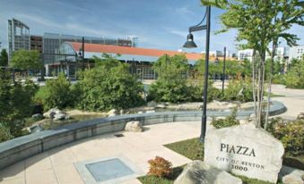 "a large stone sign reading "" piazza "" is displayed in front of a building and a park" at Sonesta Select Seattle Renton Suites