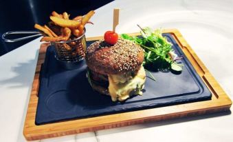 a plate of food with a burger , fries , and salad on a blue tray , sitting on a wooden table at Logis Golfe Hotel