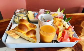 a tray with a variety of food items , including bread , fruit , and a glass of orange juice at Hotel Pelican