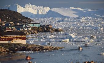 a picturesque view of a harbor with icebergs and mountains in the background , and a boat on the water at Hotel Arctic