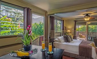 a luxurious bedroom with a king - sized bed , a balcony overlooking a lush green landscape , and a table with two glasses of orange juice at Paradise Bay Resort