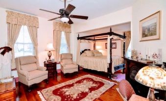 a cozy living room with wooden floors , white walls , and a large four - poster bed in the center at Colonial Beach Plaza Bed & Breakfast
