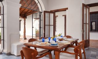 a dining room with a wooden table set for six people , surrounded by white walls and a brick archway at San Rafael