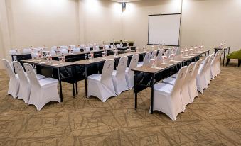 a conference room set up for a meeting , with rows of tables and chairs arranged in a semicircle at De Baghraf by Amithya