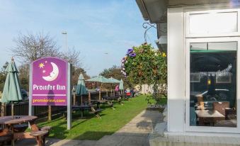 "a sign for "" faith inn "" with a moon design in front of a building and greenery" at Premier Inn Littlehampton
