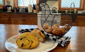 a dining table with a plate of bread , a basket of bread rolls , and a cup of coffee at Fat Sheep Farm & Cabins