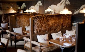 a cozy dining area with wooden furniture , including a dining table and chairs , surrounded by white fur , under a chandelier at The White Horse