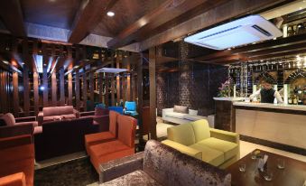 a modern lounge area with colorful chairs and couches , along with a bar in the background at Hotel CH2