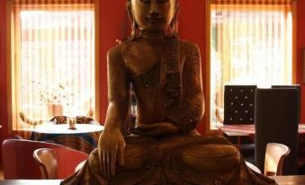 a statue of a buddha is sitting on a table in front of a window at Hotel Kerala