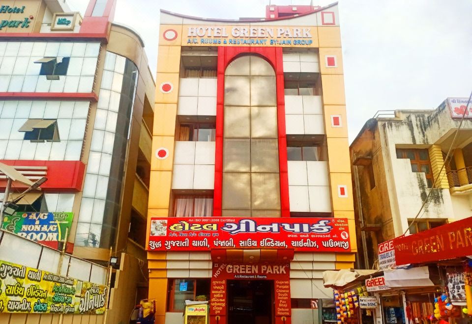 a building with a red and yellow facade is surrounded by other buildings and advertisements at Hotel Greenpark