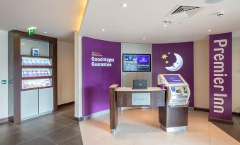 "a room with a purple wall and a desk with a laptop on it , along with a sign that says "" good night guarantee .""." at Premier Inn Melton Mowbray