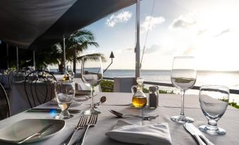 a table is set with silverware , wine glasses , and a bottle of wine overlooking the ocean at The Palms Resort