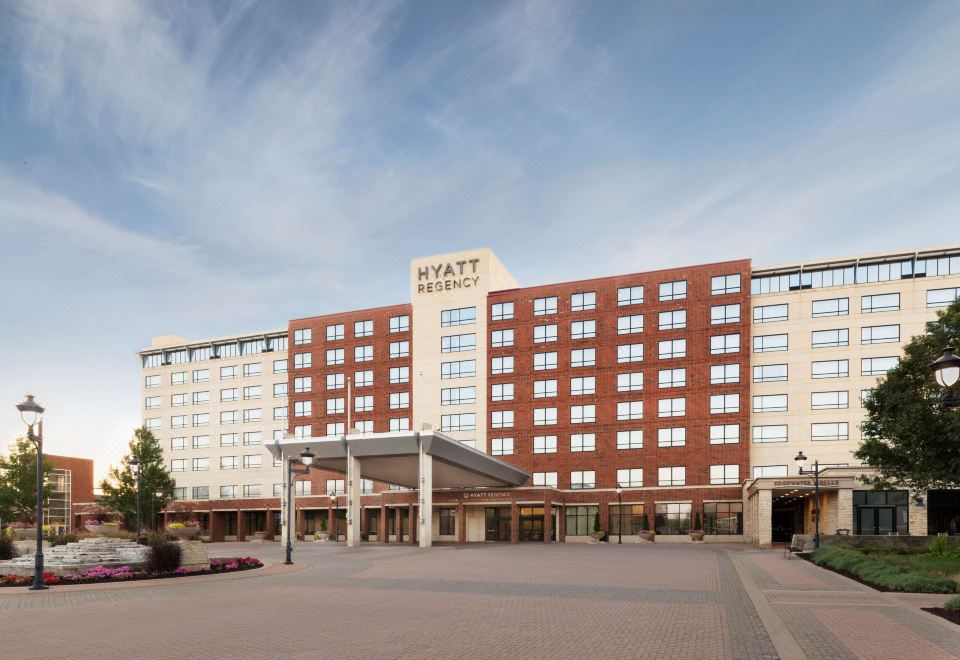 a large hotel with a red and brown facade , situated in front of a parking lot at Hyatt Regency Coralville Hotel & Conference Center