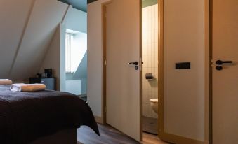 a bedroom with a bed and a window , and an open door leading to a bathroom at Mr Lewis Zandvoort