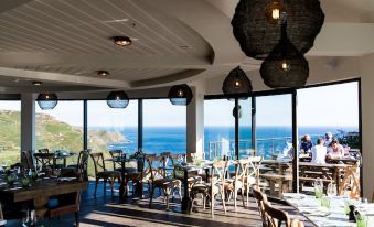 a restaurant with a dining table and chairs set up in the restaurant , overlooking the ocean at Gara Rock
