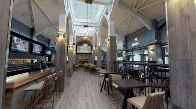 a modern , open - air bar with wooden tables and chairs , as well as a large skylight overhead at Village Hotel Liverpool