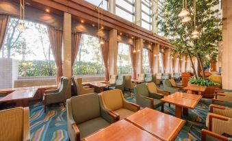 a large , modern restaurant with multiple dining tables and chairs , as well as a tree in the middle of the room at Keio Plaza Hotel Hachioji