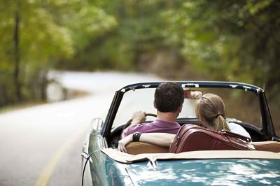 a man and a woman are driving a convertible car down a country road , with the man taking the woman at Country Inn & Suites by Radisson, Watertown, SD