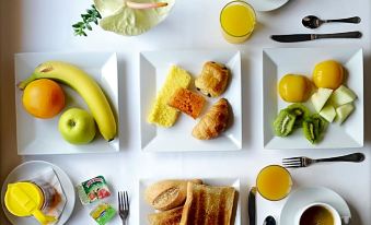 a dining table with a variety of breakfast items , including croissants , bananas , oranges , and coffee at Hotel Navarras