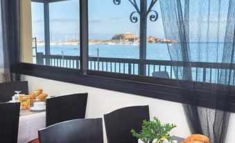 a dining table set for breakfast , with a view of the ocean through a window at Joseph Charles