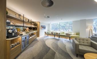 a modern restaurant with a bar area and dining tables , where people are enjoying their meals at Pullman at Sydney Olympic Park