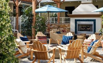 a wooden patio set with blue cushions and an umbrella , surrounded by a brick fireplace and a patio area with tables and chairs at Hotel Carmel