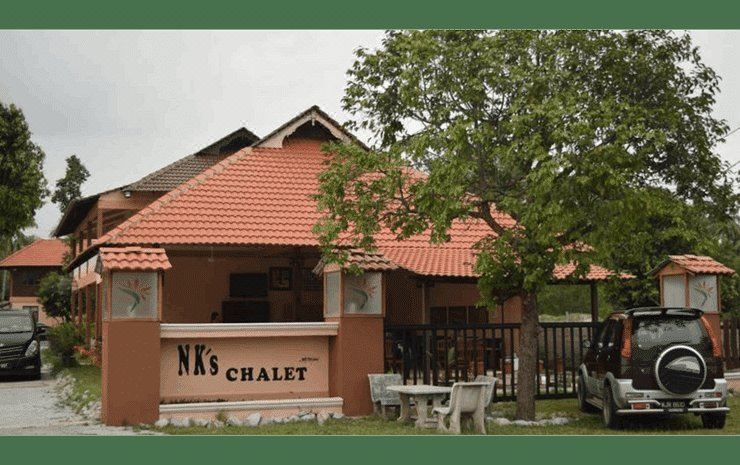 "a small , red - roofed building with a sign that reads "" nks chalet "" on the side of it" at Nks Chalet