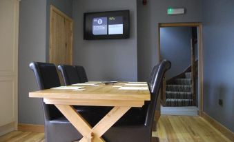 a wooden dining table with black chairs and a television mounted on the wall above it at The Feathers