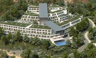 a large building with a green roof is surrounded by trees and has a swimming pool in the middle at Monchique Resort & Spa