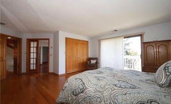 a spacious bedroom with hardwood floors , a large bed , and a door leading to a balcony at Roxbury Suites