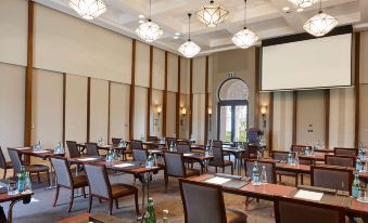 a large conference room with multiple rows of chairs arranged in a semicircle , and a projector on the wall at Banyan Tree Tamouda Bay