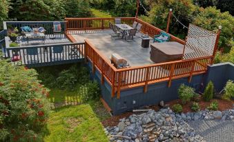 a wooden deck with a hot tub on it , surrounded by trees and grass , and a deck furniture arrangement at The Lighthouse