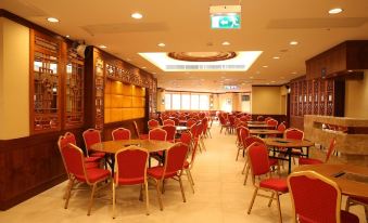 There is a restaurant with tables and chairs in the middle, as well as an empty dining room area at Grand Harbour Hotel
