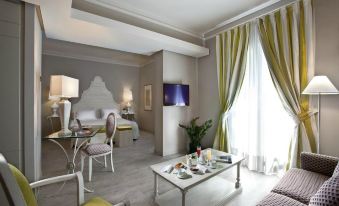 a modern living room with a gray couch , white chairs , and a glass coffee table at Grand Hotel Baia Verde